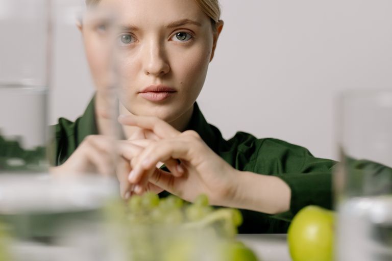 Woman in green shirt sits at the table with fruits, creating a serene and minimalist composition.